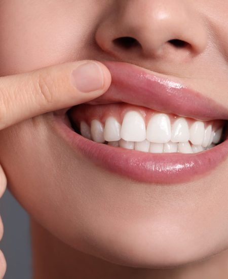 Young woman showing healthy gums on grey background, closeup